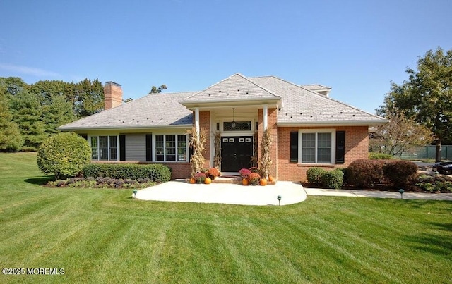 view of front of property with a front lawn, a chimney, and brick siding