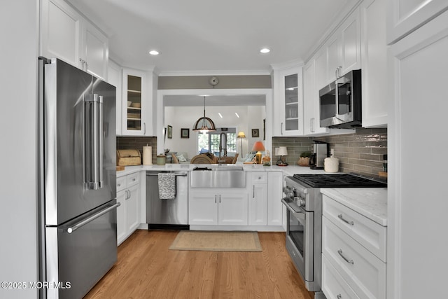 kitchen featuring high quality appliances, light wood-style flooring, white cabinetry, glass insert cabinets, and recessed lighting