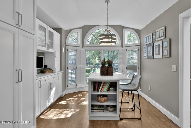 dining area with vaulted ceiling, wood finished floors, and baseboards
