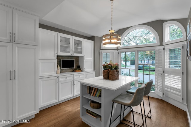 kitchen with white cabinets, a kitchen breakfast bar, open shelves, wood finished floors, and vaulted ceiling