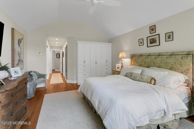 bedroom with wood finished floors, a closet, lofted ceiling, and a ceiling fan