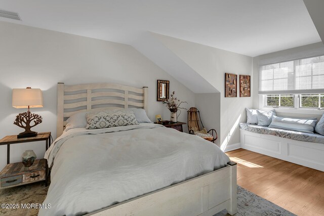 bedroom with wood finished floors, baseboards, and vaulted ceiling