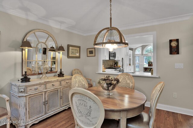dining area featuring wood finished floors, baseboards, and ornamental molding