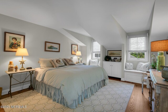 bedroom featuring light wood-type flooring, multiple windows, lofted ceiling, and baseboards