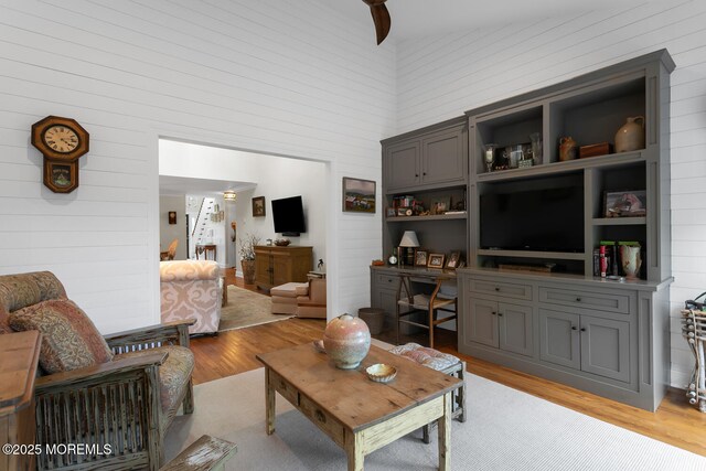 living area featuring wood walls, light wood-style flooring, and a towering ceiling