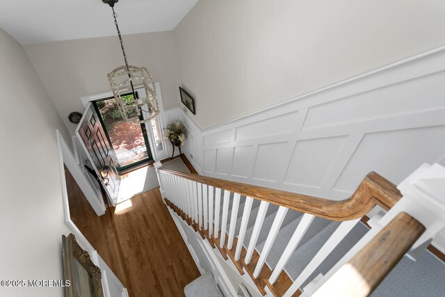 stairs featuring a decorative wall, wood finished floors, and a wainscoted wall