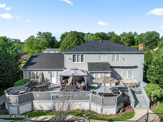 19 Dartmoor Dr, Manalapan, NJ 07726 - rear view of house featuring a gazebo, outdoor dining space, a wooden deck, a chimney, and view of wooded area