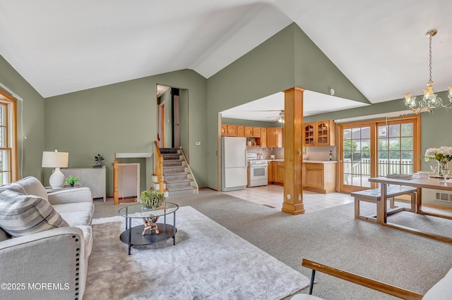 living area with vaulted ceiling, light colored carpet, a chandelier, stairs, and decorative columns