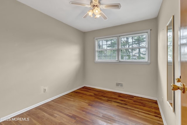 spare room with baseboards, hardwood / wood-style floors, and a ceiling fan
