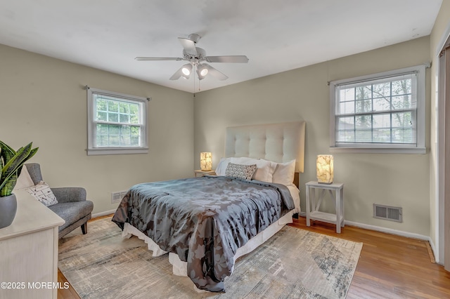 bedroom with multiple windows, wood finished floors, baseboards, and a ceiling fan