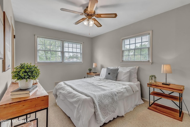 carpeted bedroom with multiple windows, baseboards, and a ceiling fan