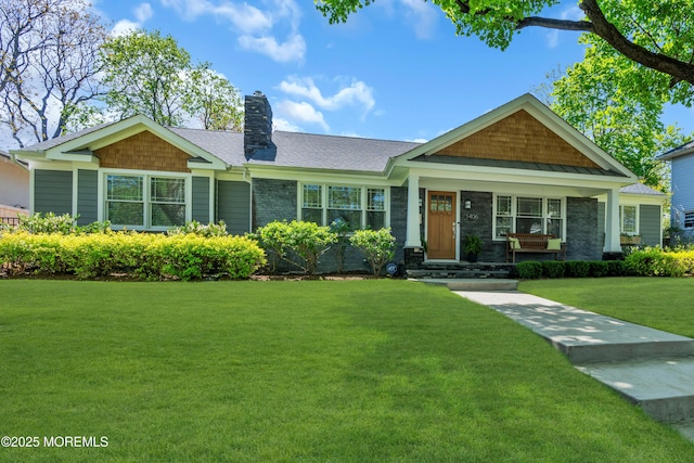 craftsman-style home featuring a front lawn, a chimney, covered porch, and a shingled roof