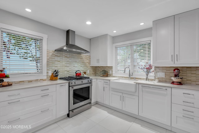 kitchen featuring stainless steel range with gas cooktop, wall chimney exhaust hood, a sink, tasteful backsplash, and light tile patterned floors