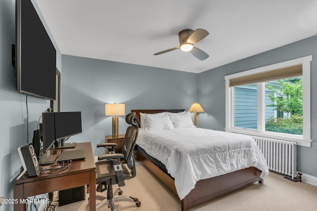 bedroom with radiator, carpet flooring, a desk, baseboards, and a ceiling fan