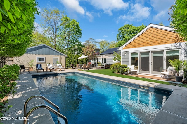 outdoor pool with a patio area, french doors, and an outbuilding
