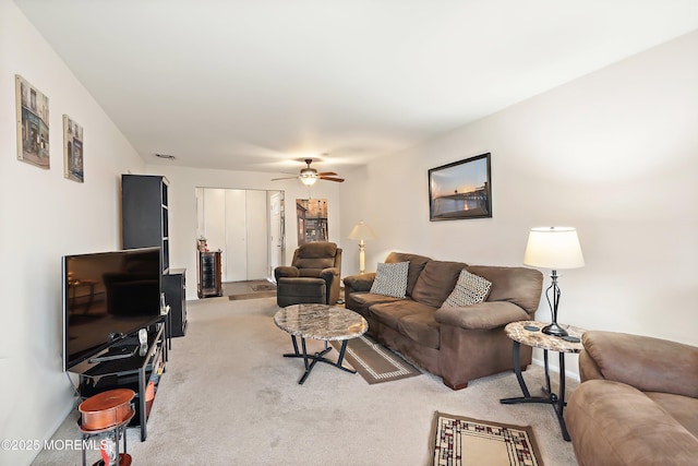 living area featuring light carpet and ceiling fan