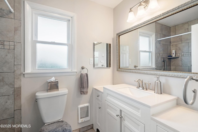 full bath featuring a tile shower, plenty of natural light, toilet, and vanity