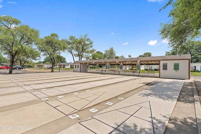 view of property's community featuring covered and uncovered parking and shuffleboard