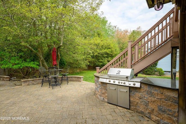 view of patio / terrace featuring stairs, outdoor dining space, grilling area, and an outdoor kitchen