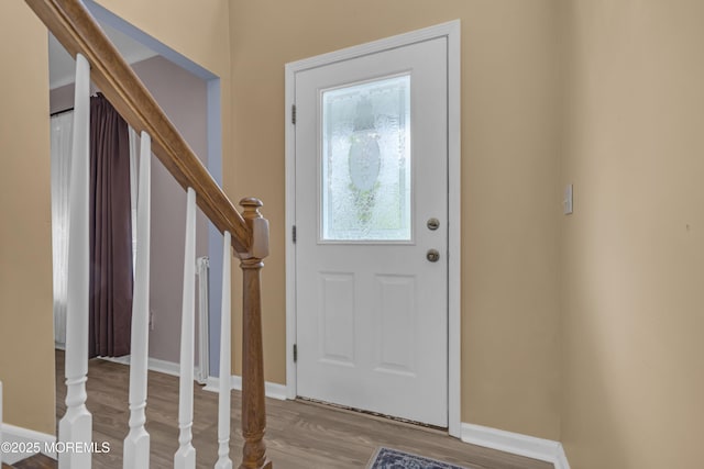 foyer entrance featuring wood finished floors, stairs, and baseboards