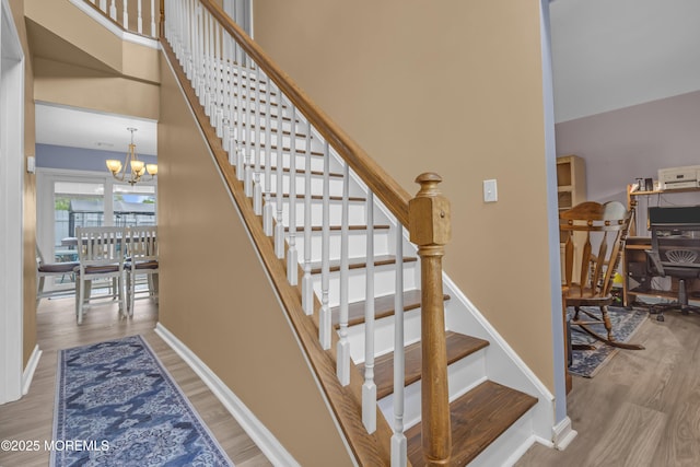stairway with wood finished floors, a chandelier, and baseboards