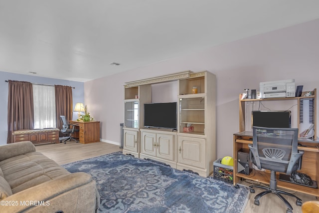 living area with wood finished floors, an office area, and baseboards
