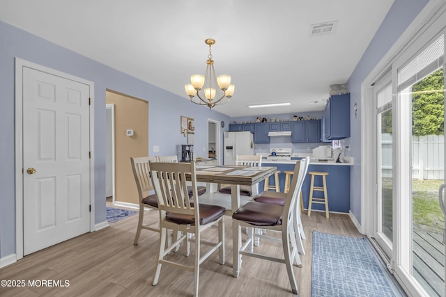 dining room with a chandelier, light wood-style floors, and baseboards
