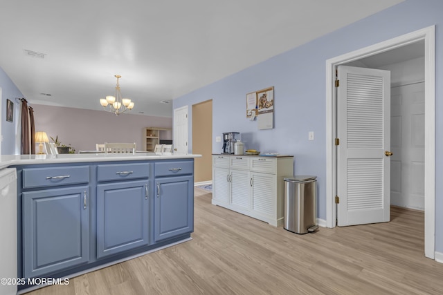 kitchen featuring blue cabinets, a chandelier, light wood finished floors, and hanging light fixtures