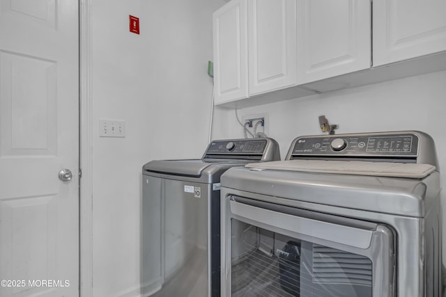 clothes washing area with washing machine and clothes dryer and cabinet space