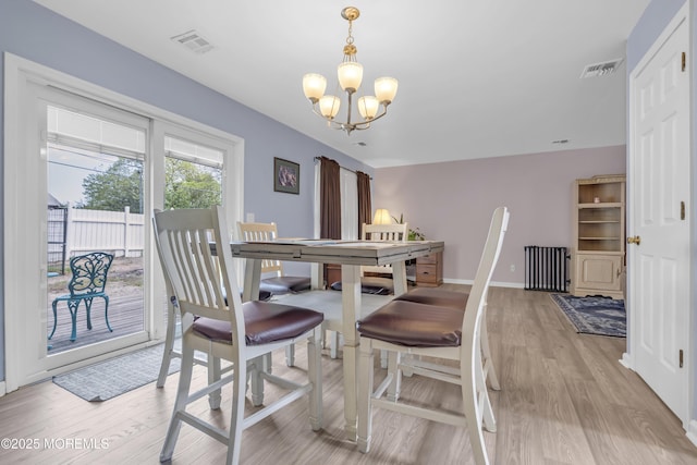 dining space with a chandelier, light wood finished floors, and baseboards