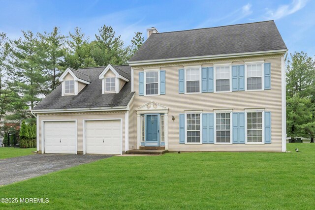 view of front of house with asphalt driveway, a garage, a front yard, and a chimney
