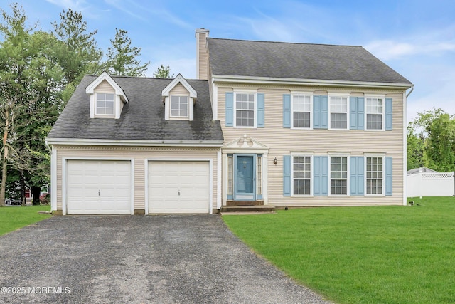 colonial inspired home with asphalt driveway, a garage, a chimney, and roof with shingles