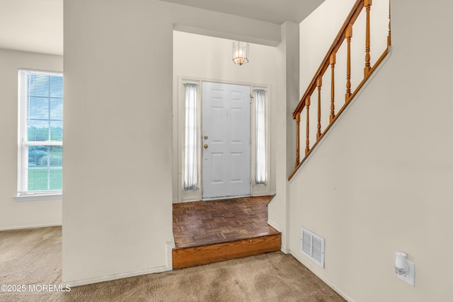 carpeted foyer entrance featuring plenty of natural light, stairs, and baseboards