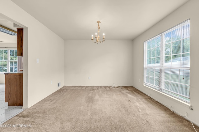 unfurnished room featuring a chandelier and light carpet