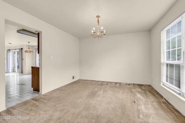 tiled spare room featuring a chandelier and carpet flooring