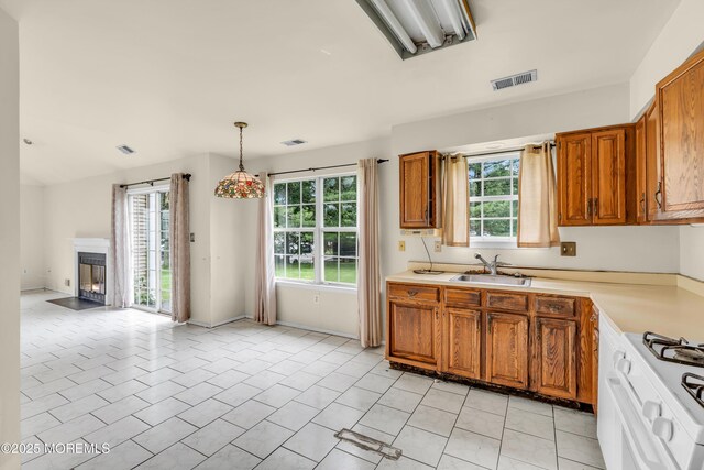 kitchen with a sink, plenty of natural light, brown cabinetry, and light countertops