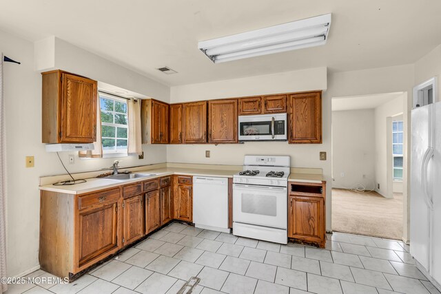 kitchen featuring white appliances, brown cabinets, a sink, and light countertops