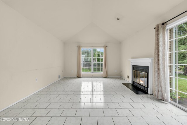 unfurnished living room featuring a fireplace with flush hearth, vaulted ceiling, plenty of natural light, baseboards, and light tile patterned floors