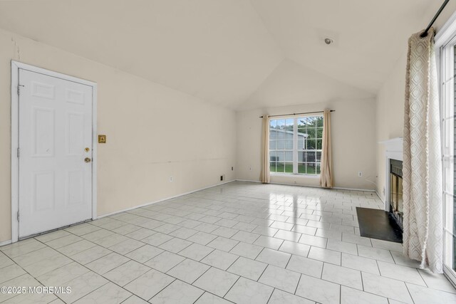 unfurnished living room with lofted ceiling, a glass covered fireplace, and baseboards
