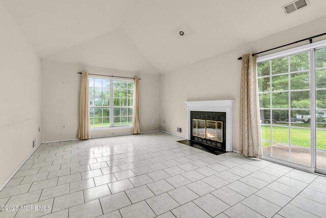 unfurnished living room featuring vaulted ceiling, a fireplace with flush hearth, and tile patterned flooring