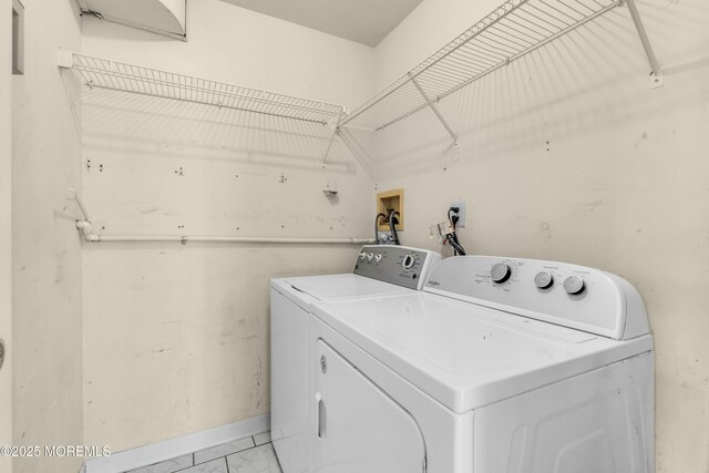 laundry area featuring independent washer and dryer, light marble finish flooring, and baseboards