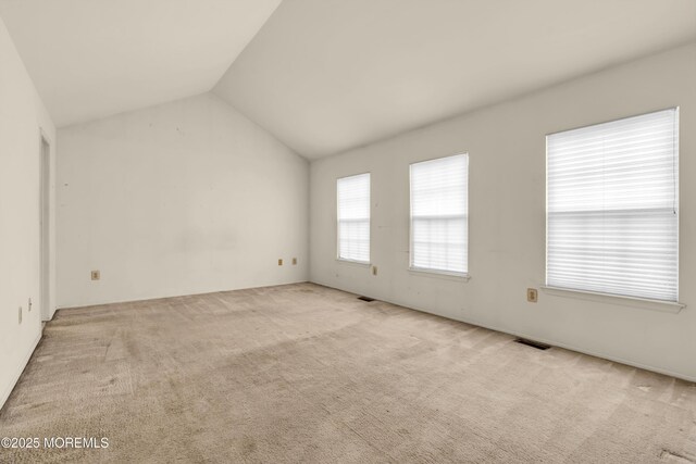 carpeted spare room with vaulted ceiling