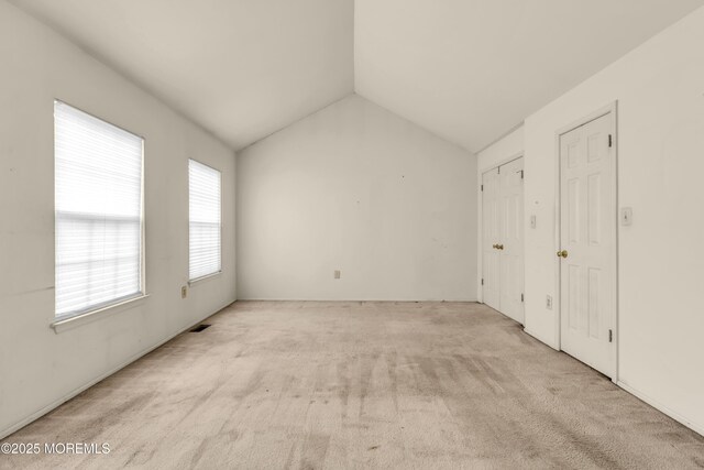 unfurnished bedroom featuring lofted ceiling and carpet floors