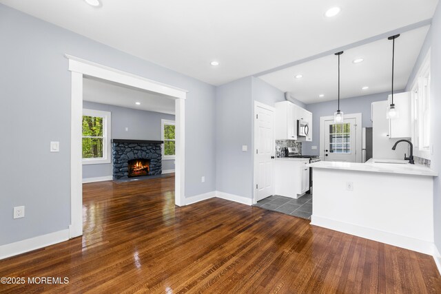 kitchen featuring dark wood-style flooring, white cabinetry, a sink, baseboards, and recessed lighting