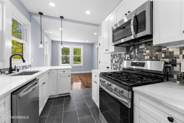 kitchen featuring appliances with stainless steel finishes, a sink, white cabinets, decorative backsplash, and recessed lighting