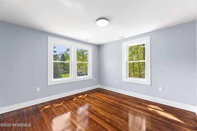 empty room featuring baseboards and dark wood-type flooring