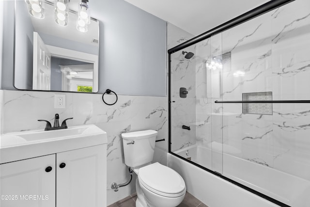 full bath featuring tile walls, toilet, vanity, and combined bath / shower with glass door
