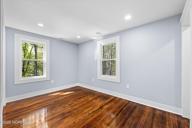spare room with dark wood-type flooring, healthy amount of natural light, baseboards, and recessed lighting