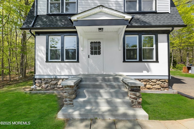 view of front of home with a shingled roof and a front yard