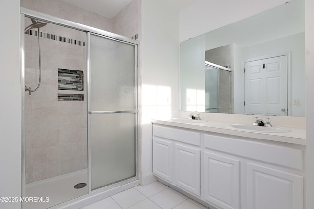 bathroom featuring a shower stall, tile patterned floors, double vanity, and a sink
